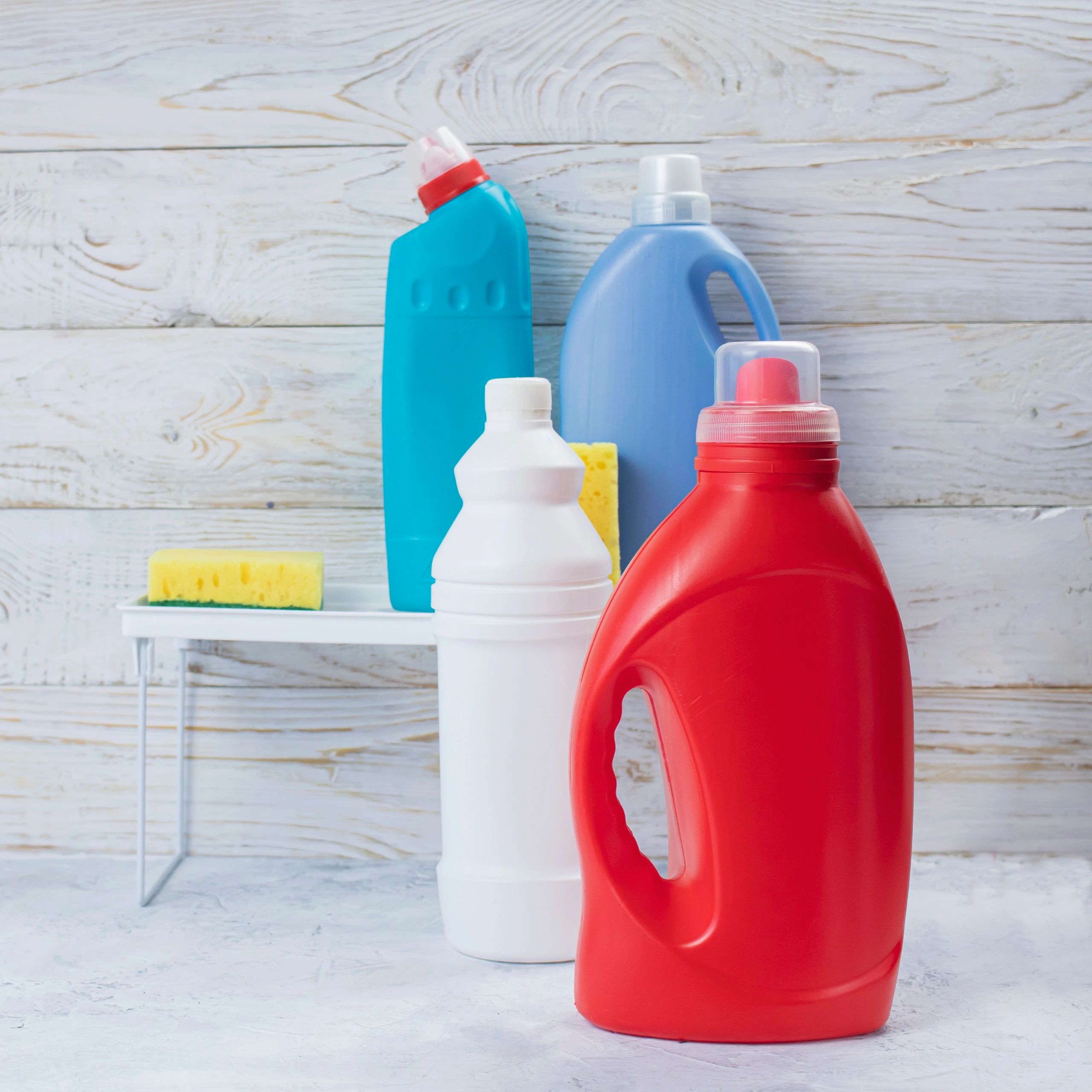 Household cleaning products and sponges on wooden background, assortment of cleaning products on shelf